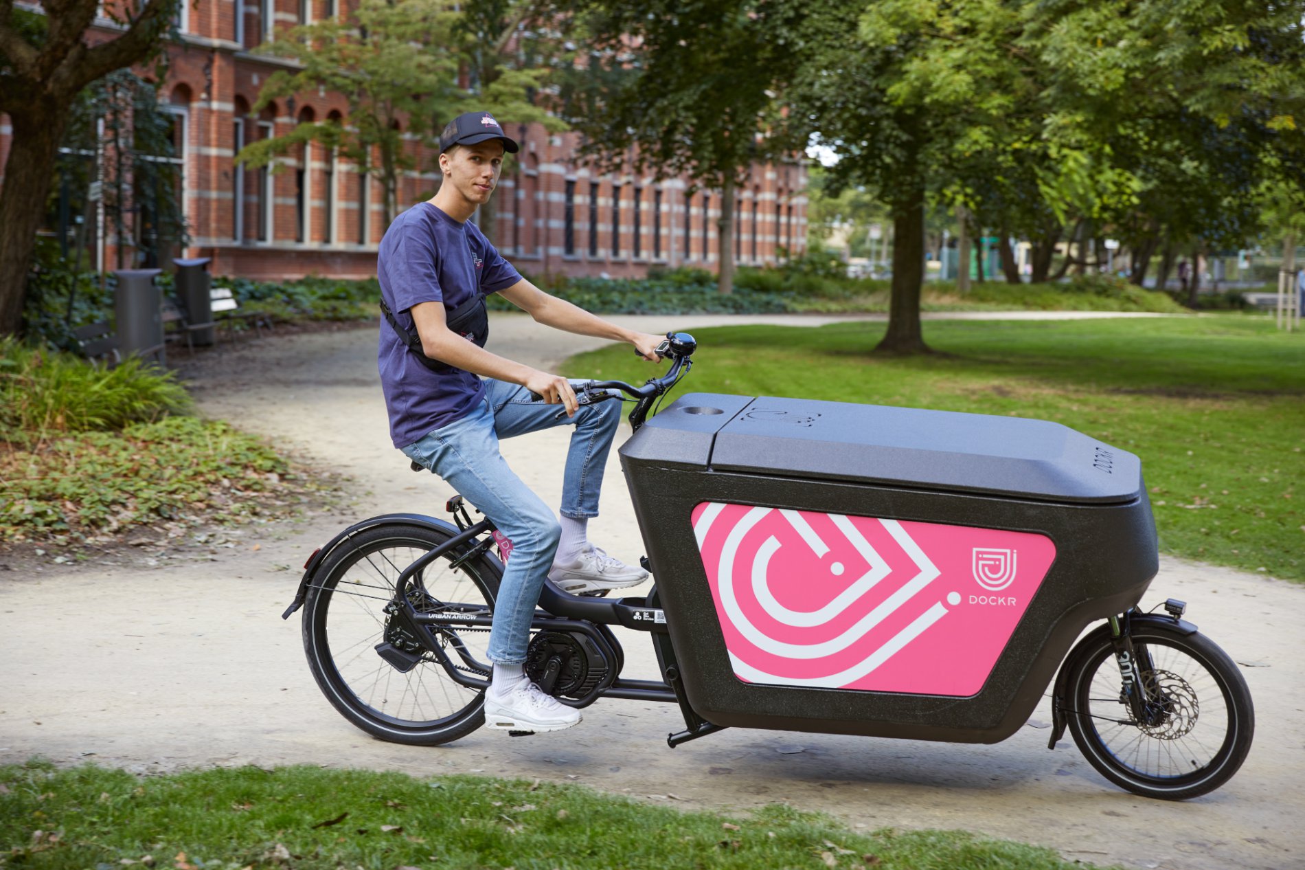 DOCKR cargo bike with box, ridden in a park